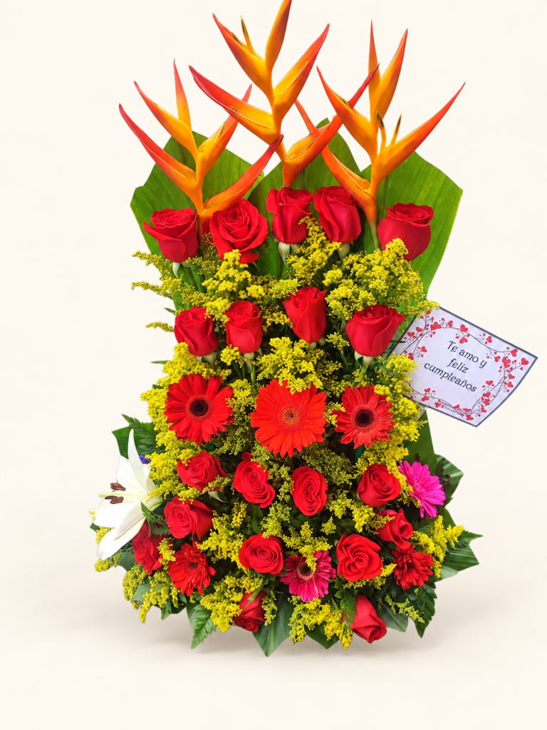 Arreglo vertical con heliconias, rosas rojas, gerberas y flores de acompañamiento. Sobre fondo crema.