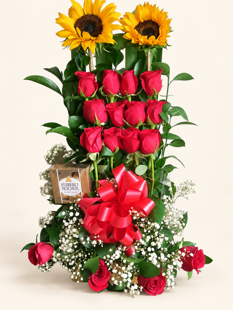 Rosas rojas y girasoles en arreglo vertical, con chocolates Ferrero Rocher y lazo rojo. Sobre fondo crema.