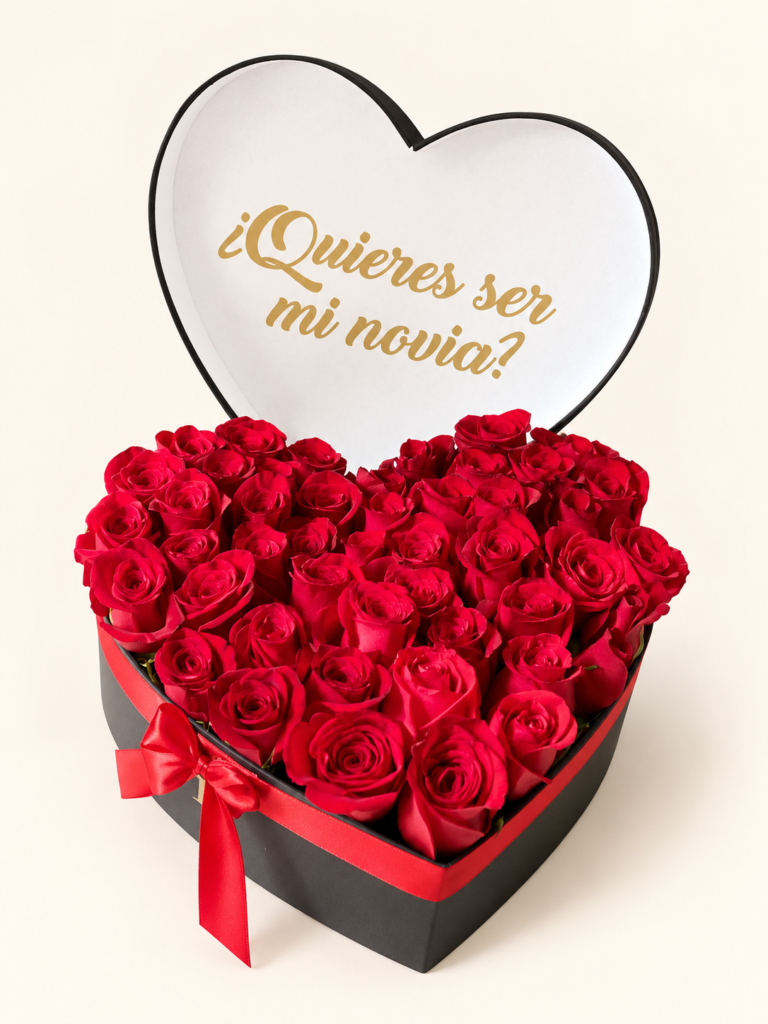 Corazón de rosas rojas en caja negra con tapa y mensaje «¿Quieres ser mi novia?». Sobre fondo crema.