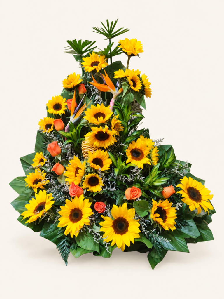 Arreglo de girasoles y rosas salmón con flores tropicales y follaje verde. Sobre fondo crema.