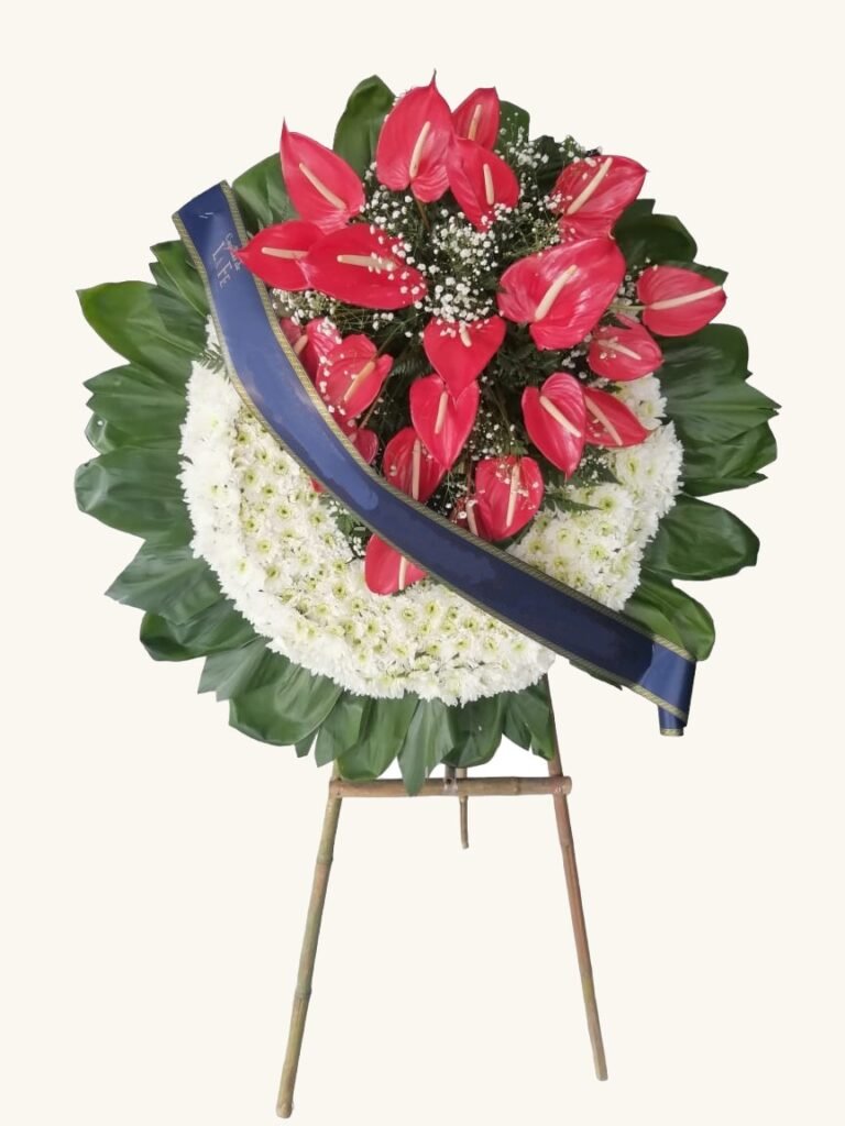 Corona fúnebre de anturios rojos con cinta azul para condolencias en Manizales