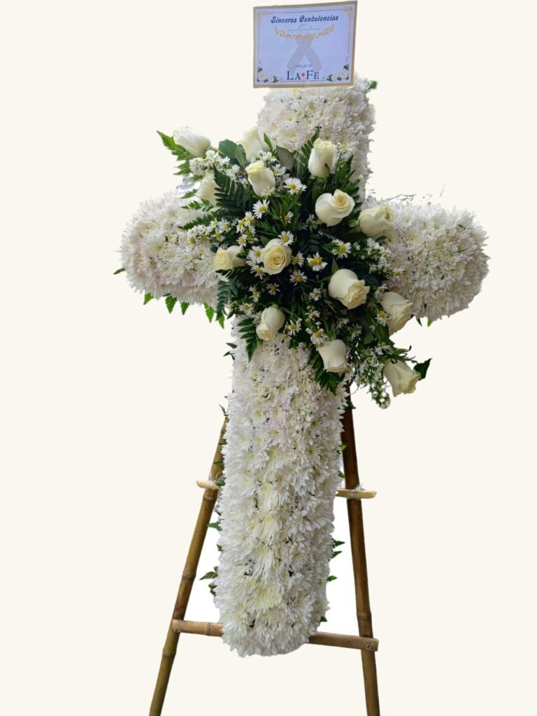 Cruz fúnebre blanca con rosas y follaje para condolencias en Manizales