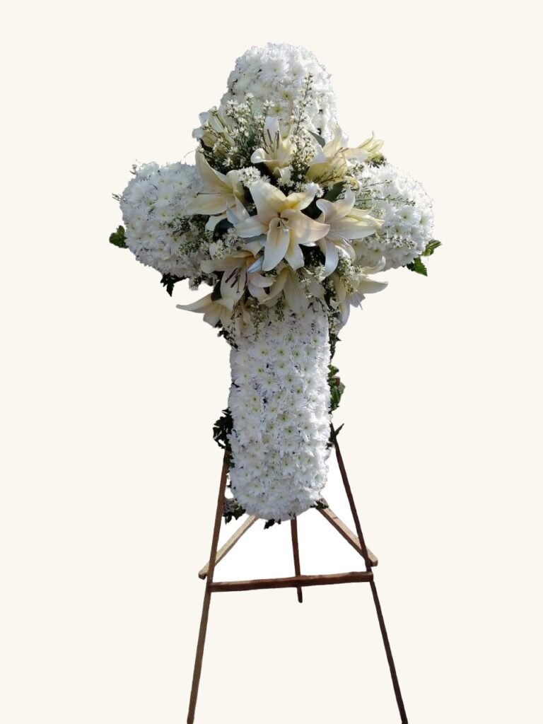 Cruz fúnebre de flores blancas y follaje para condolencias en Manizales