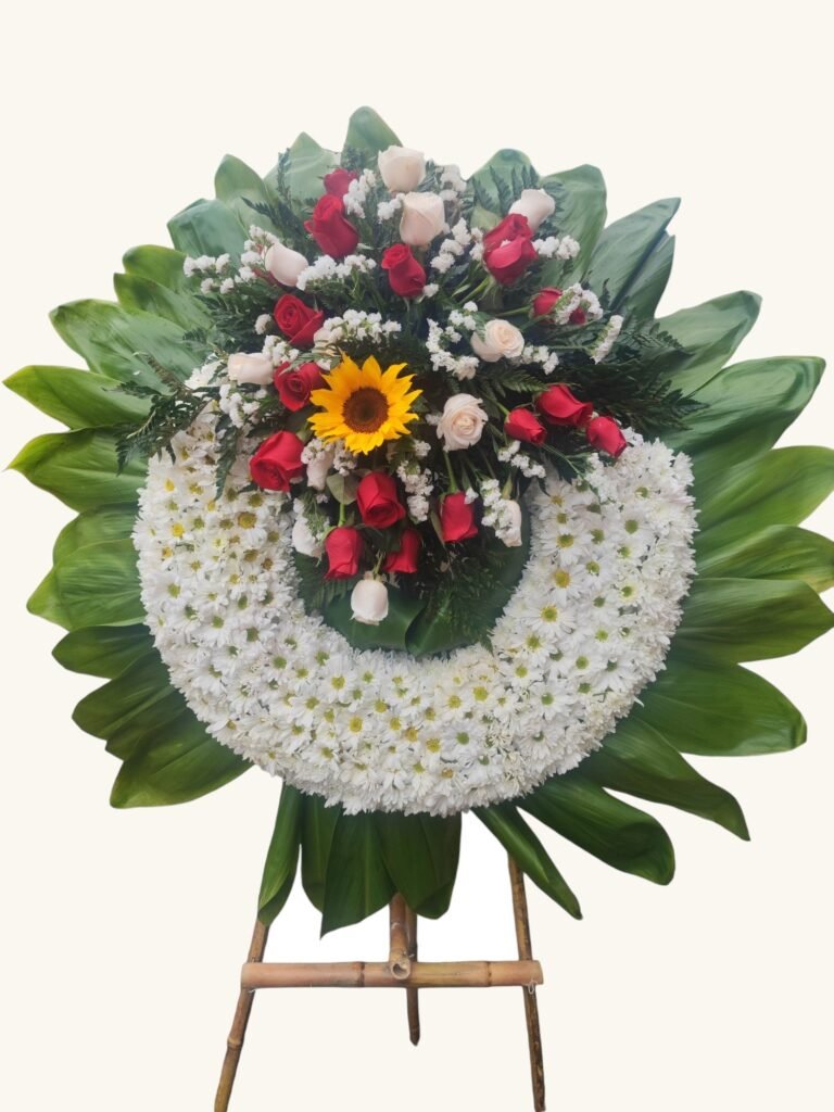 Corona fúnebre de rosas rojas y blancas con girasol para condolencias en Manizales