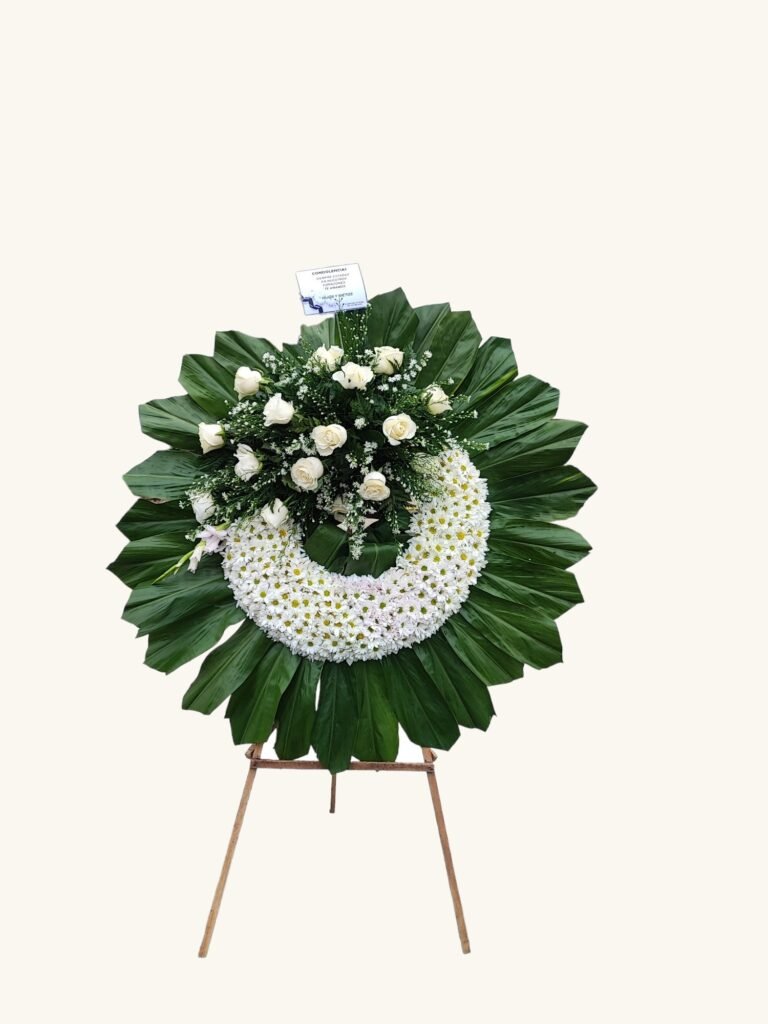 Corona fúnebre de flores blancas y follaje verde para condolencias en Manizales